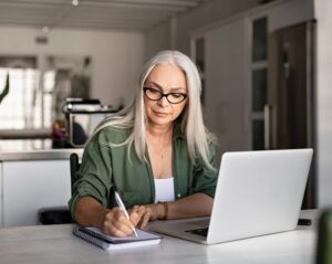 Woman using a laptop for email and taking notes.